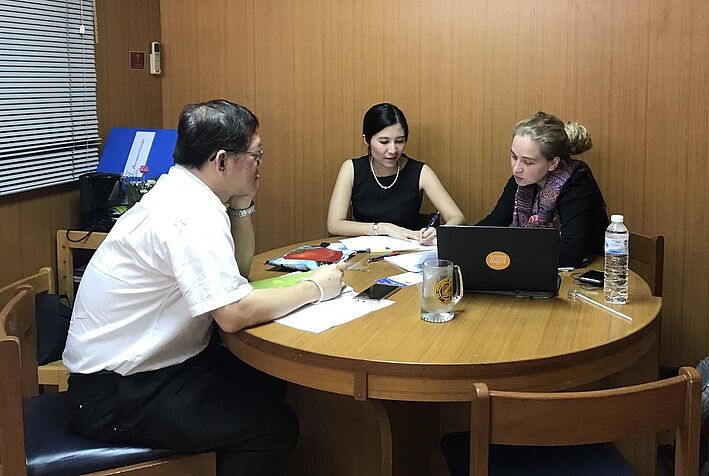 two women and a man sitting at a table with a notepad and a laptop